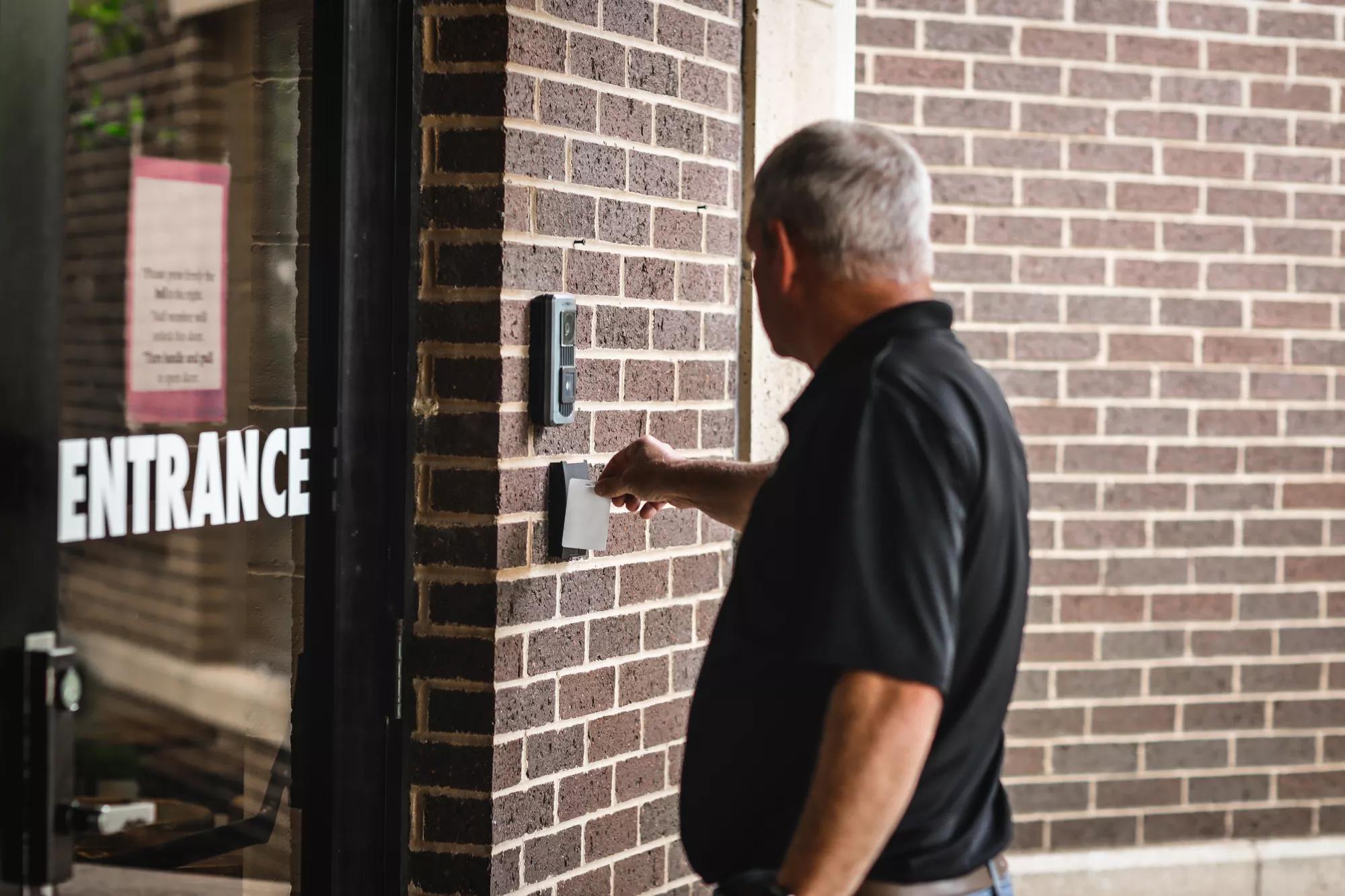 person swiping card reader on door using commercial smart lock access control credentials