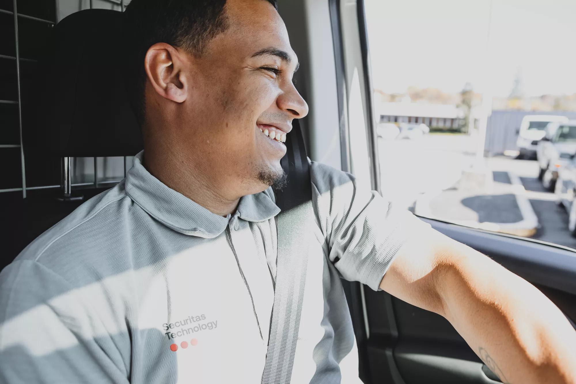 a smiling technician seated in a car, representing Securitas Technology's mobile response and commitment to delivering security service excellence