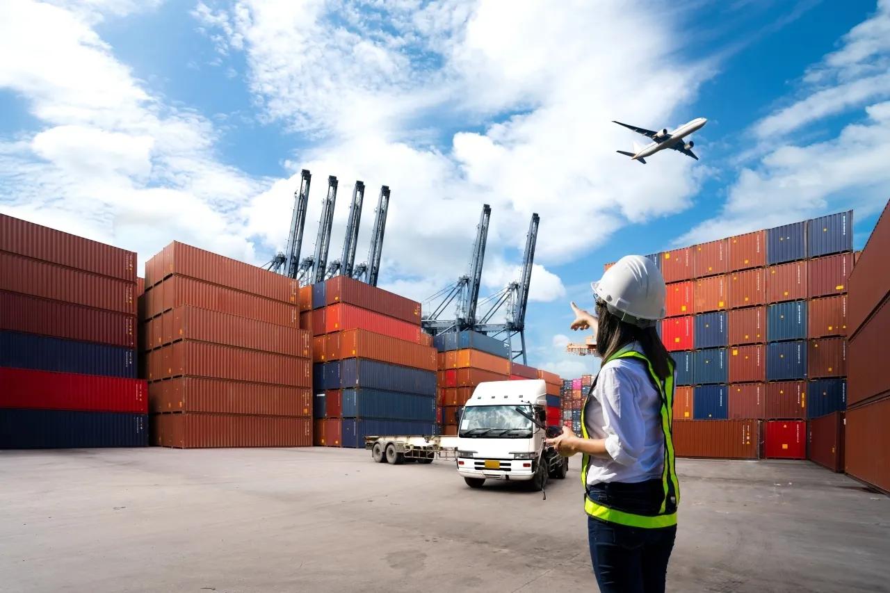 Foreman Woman control loading Containers box from Cargo freight ship for import export.