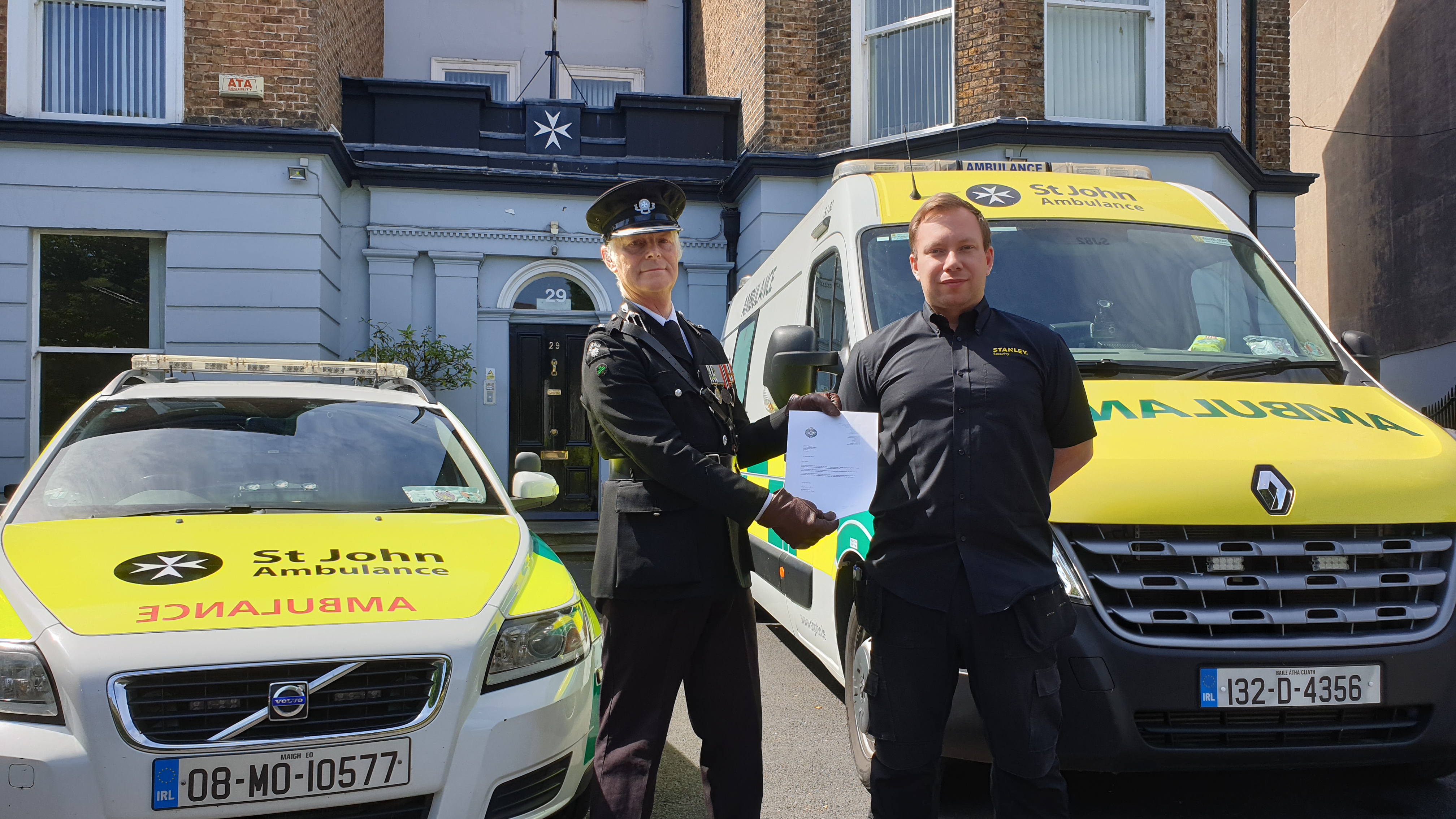 Man presented with certificate in front of ambulances