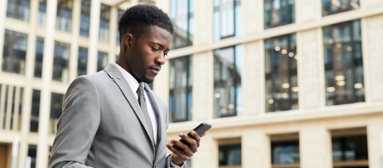 Man in suit looks at phone screen