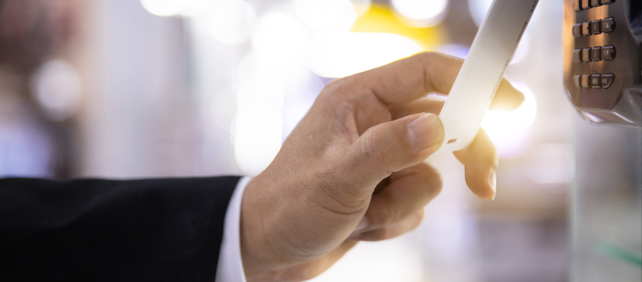 Hand holds keycard up to access control pad