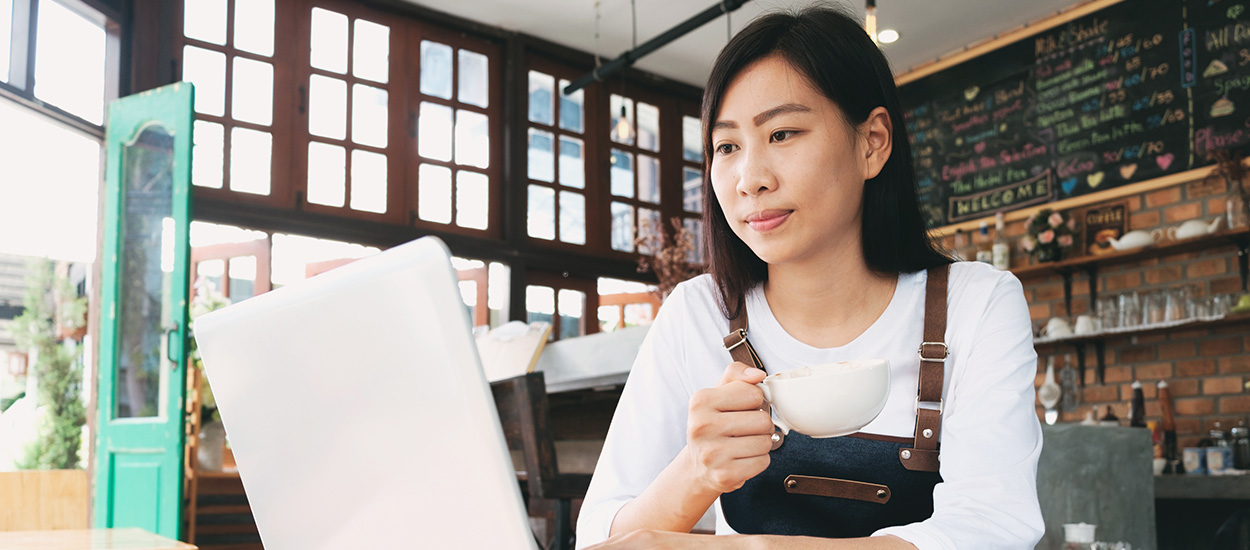 Cafe owner looks at laptop screen