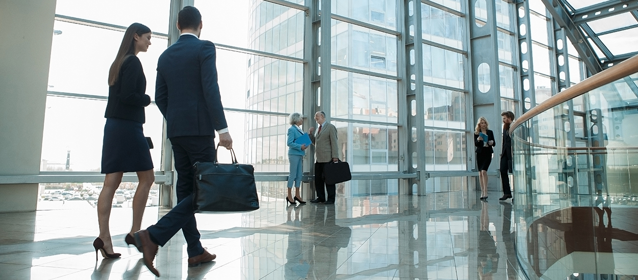 People walk through lobby of glass building