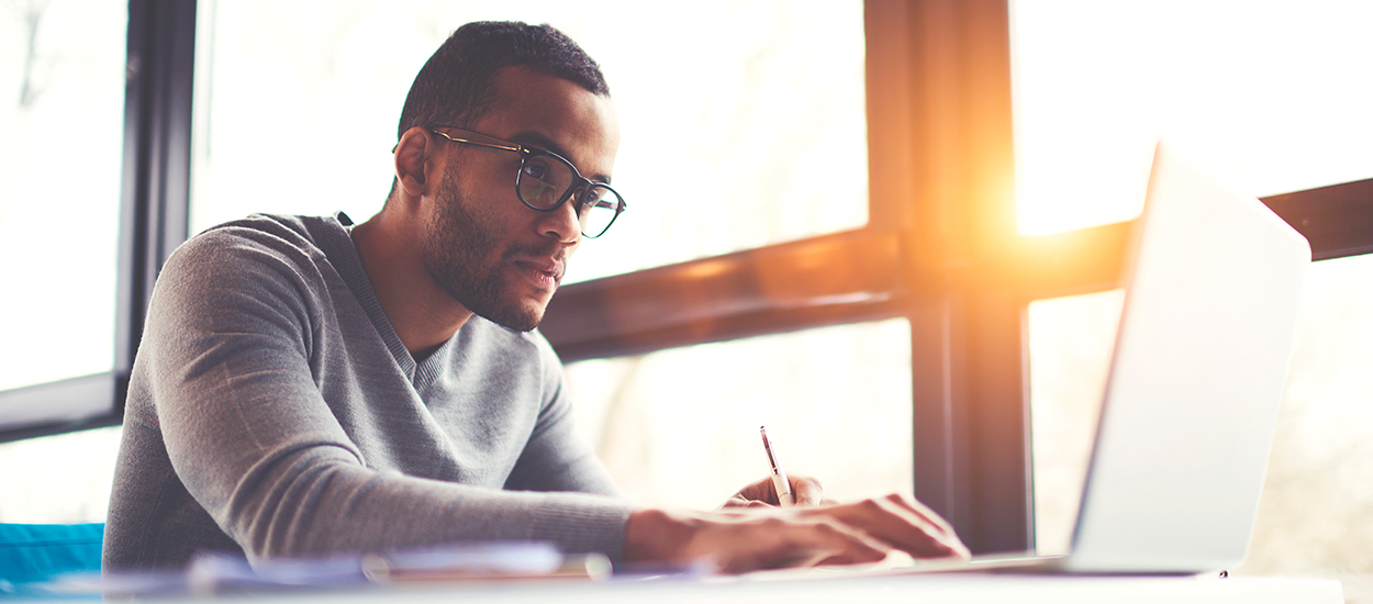 Man uses laptop in front of sunlit window