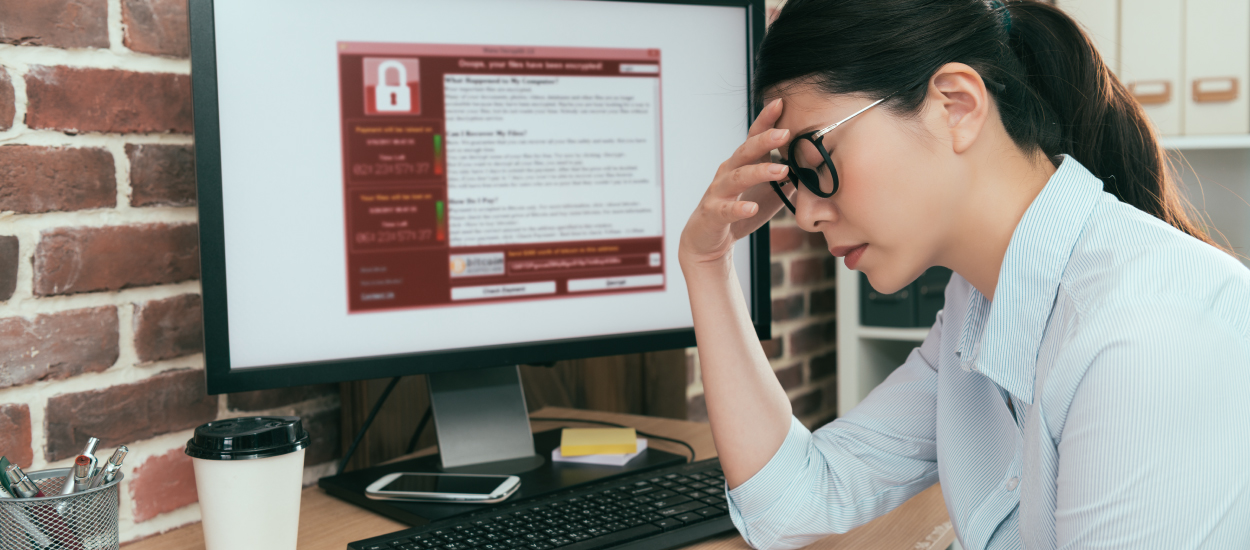 Frustrated woman holds forehead in front of computer