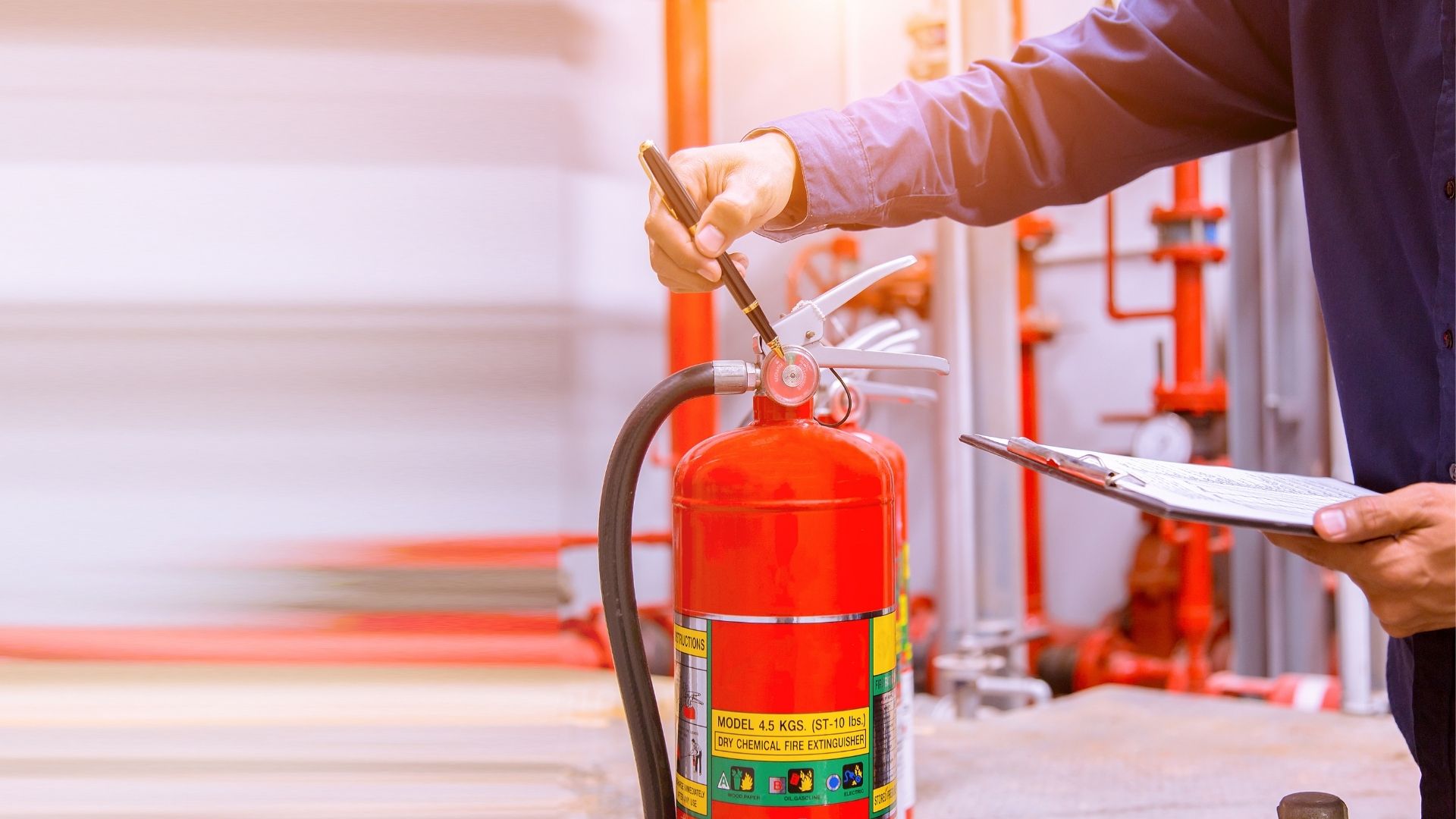 Technician holding clipboard inspects fire extinguisher