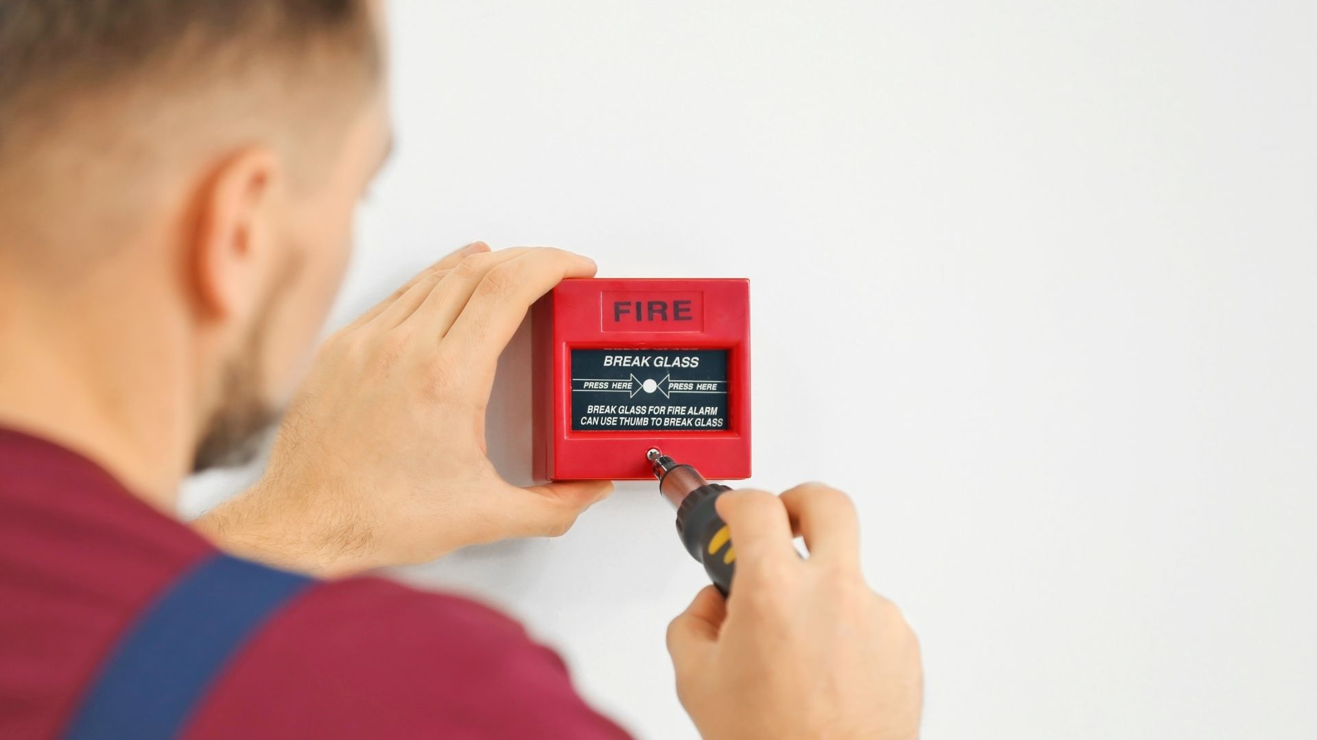 Technician installs fire alarm on wall