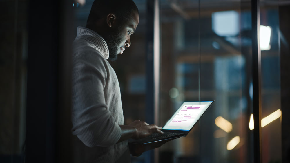 Man uses laptop in darkened room