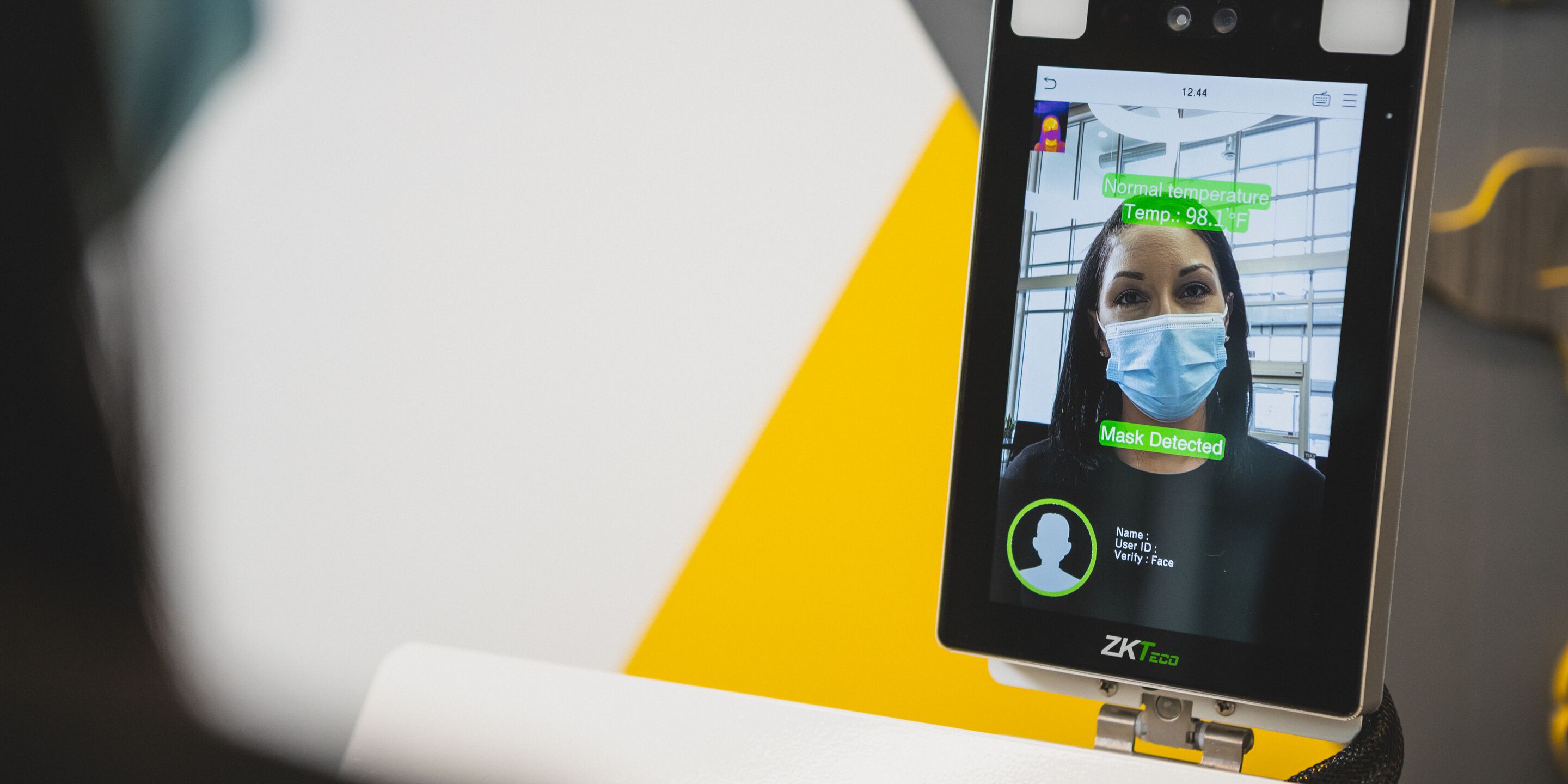 Temperature screening device scans woman wearing masks.