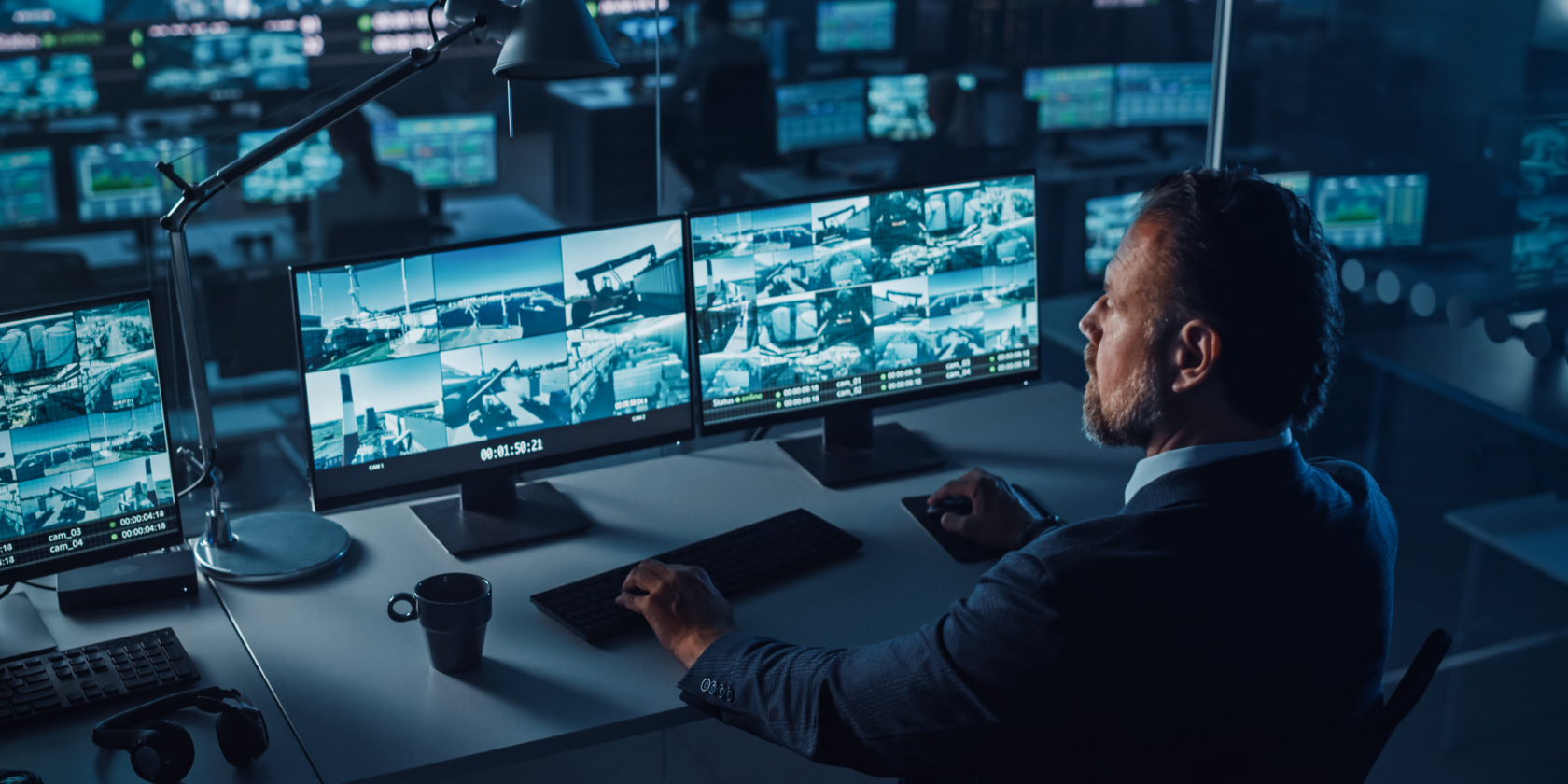 Male Officer Works on a Computer with Surveillance CCTV Video Footage