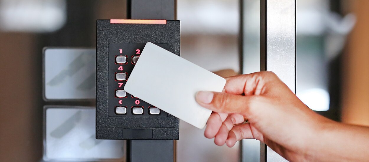 person swiping access card up next to access control card reader 