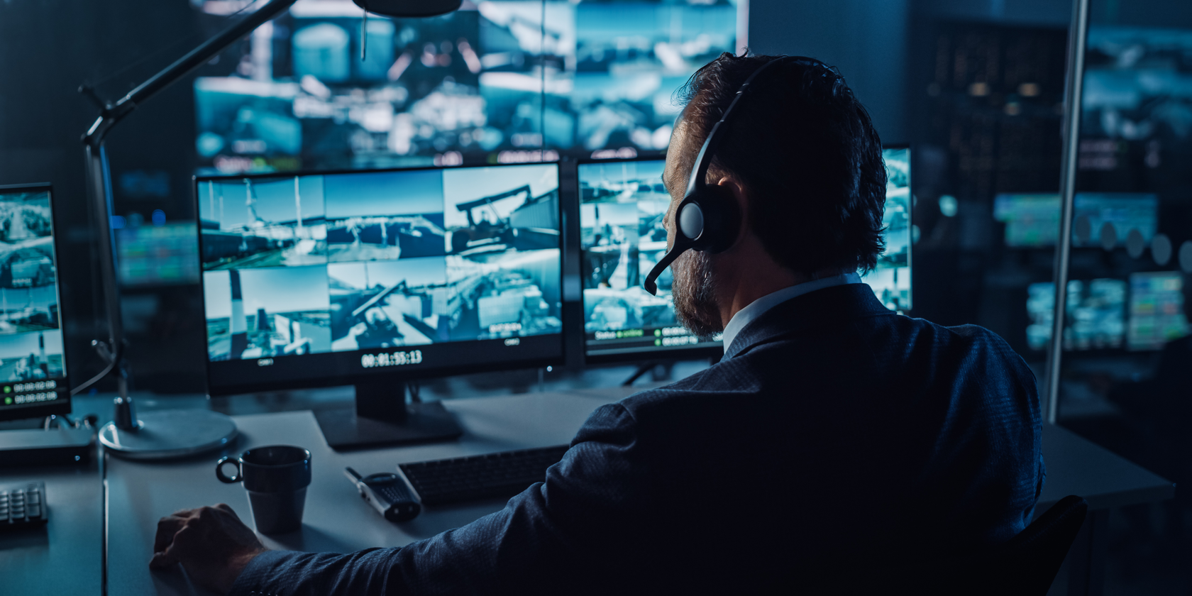 Security operator in alarm centre watching multiple screens.png