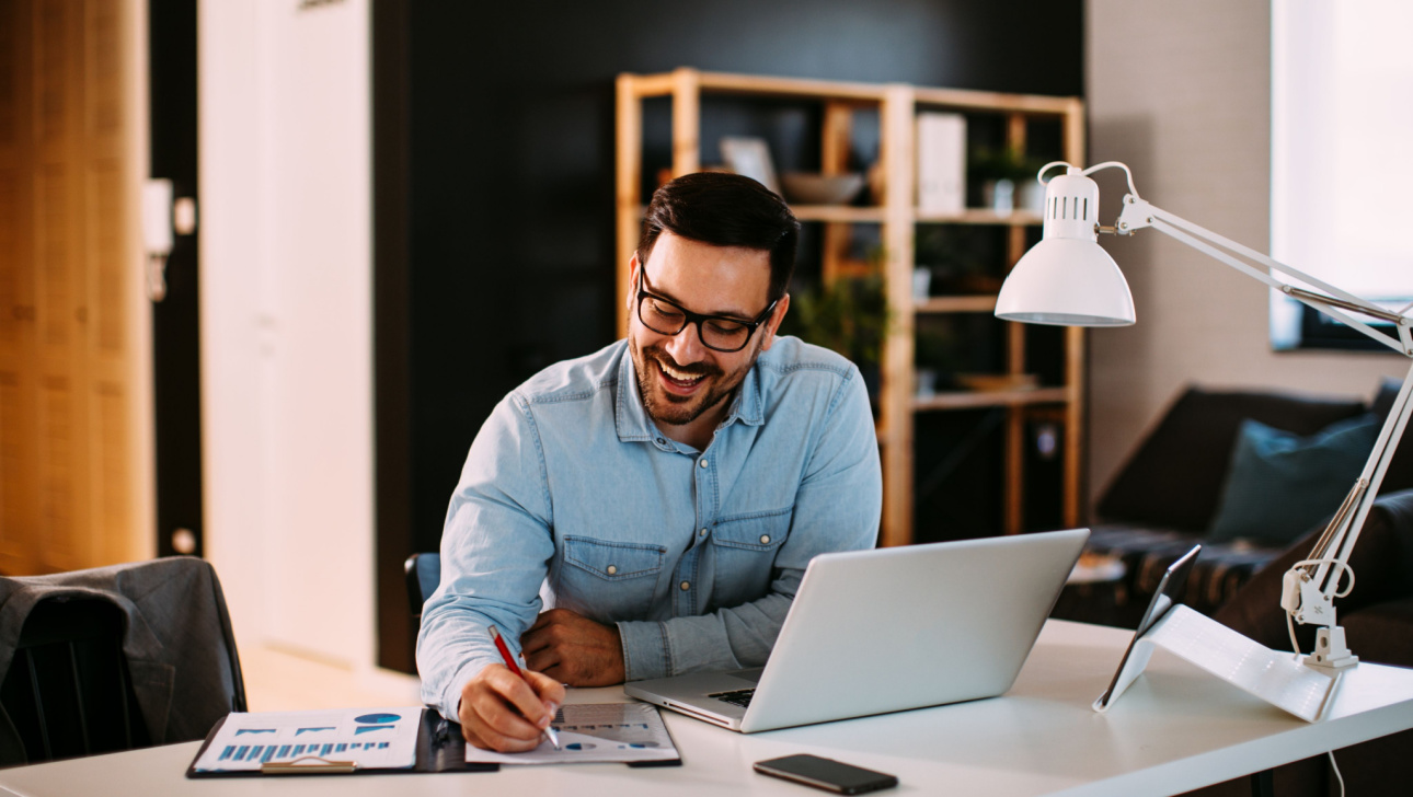 Young business man working at home with laptop and papers on desk