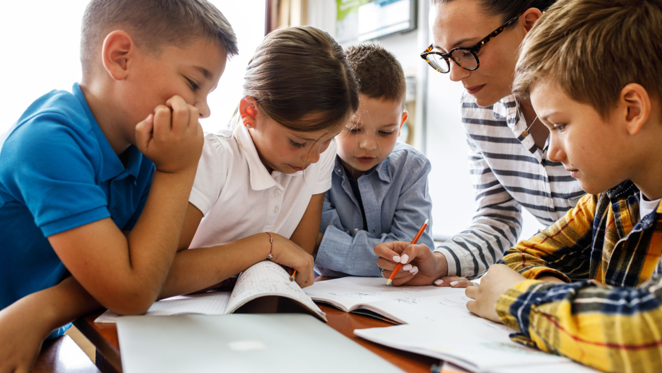 Female teacher helps school kids to finish they lesson