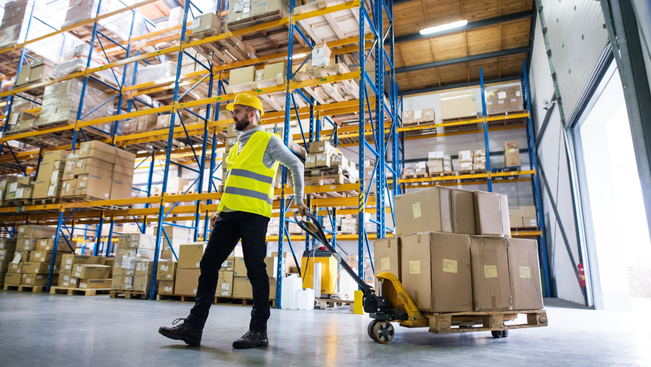 Male warehouse worker pulling a pallet truck