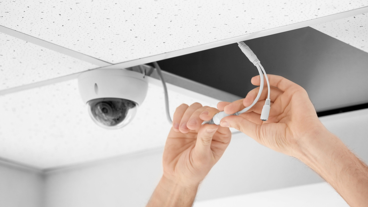 Technician installing CCTV camera on ceiling indoors