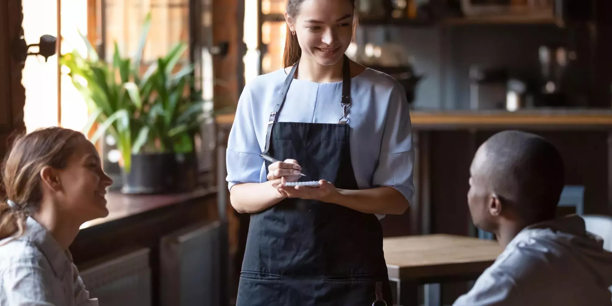 Waitress female welcoming diverse cafeteria pub guests african guy mixed race girl making order waiting staff writing wishes on notepad. Good service dining time, friends meets in public place concept