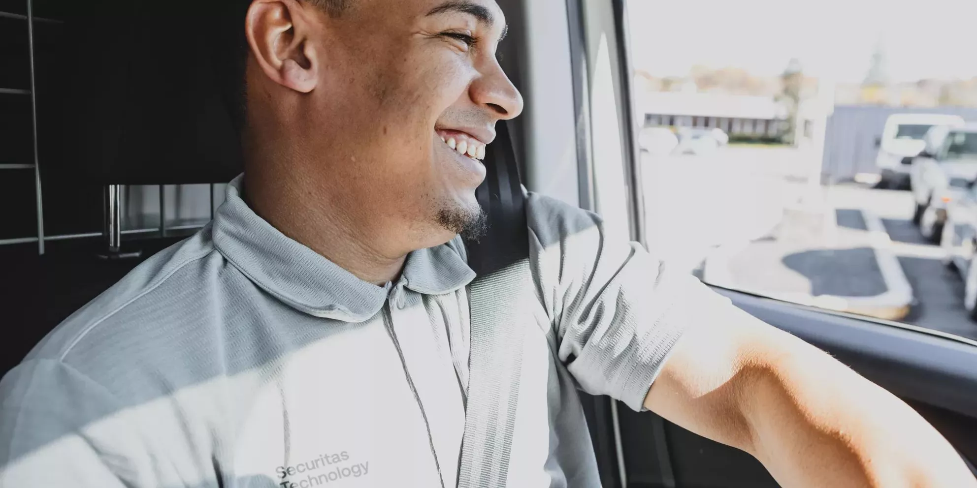 a smiling technician seated in a car, representing Securitas Technology's mobile response and commitment to delivering security service excellence