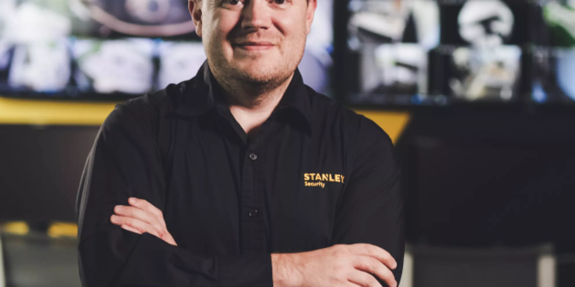 Smiling employee stands with arms crossed