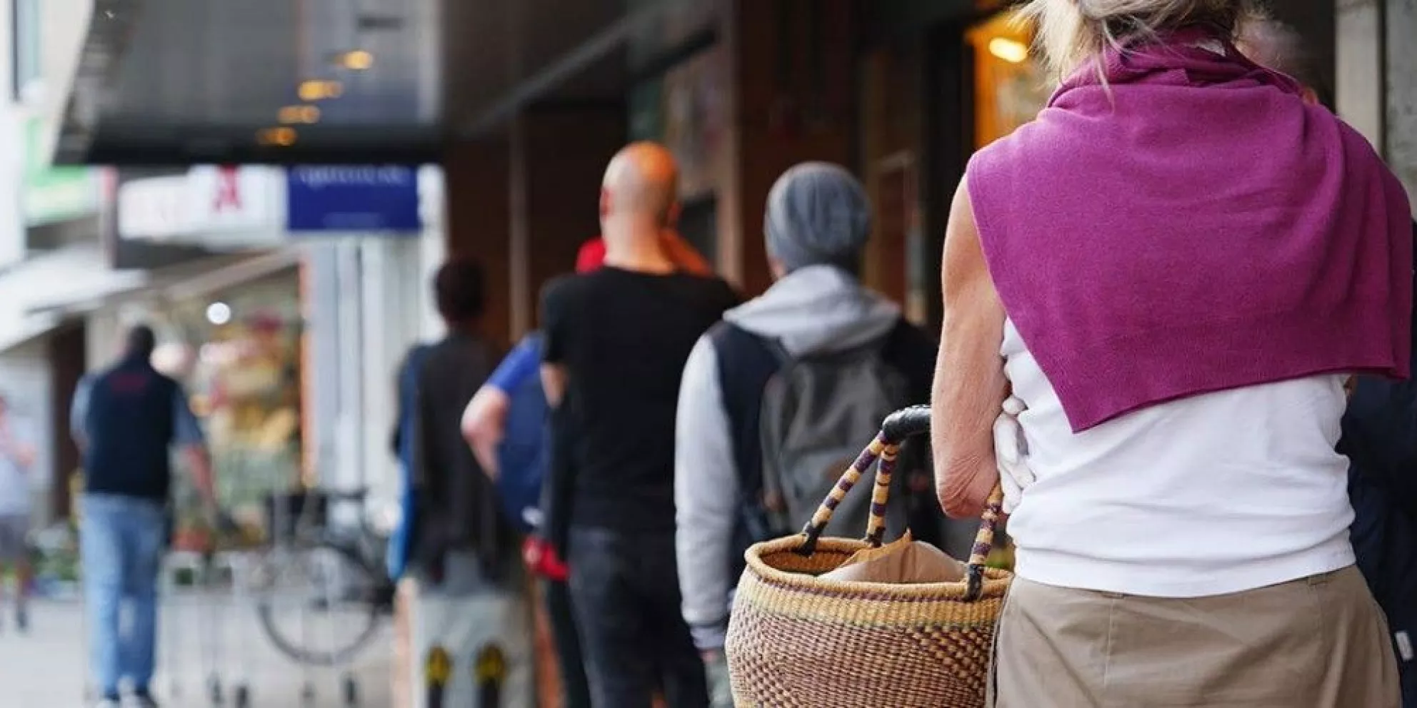 Woman carries shopping basket on busy street