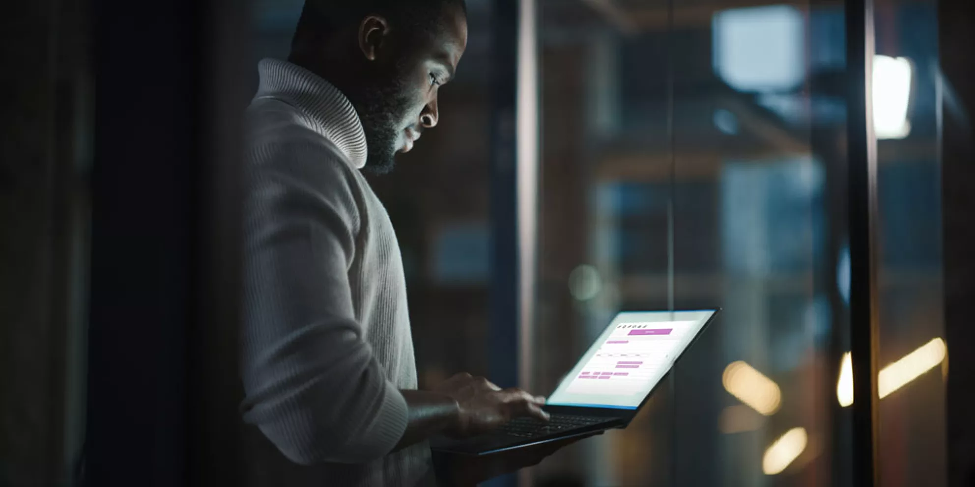 Man uses laptop in darkened room