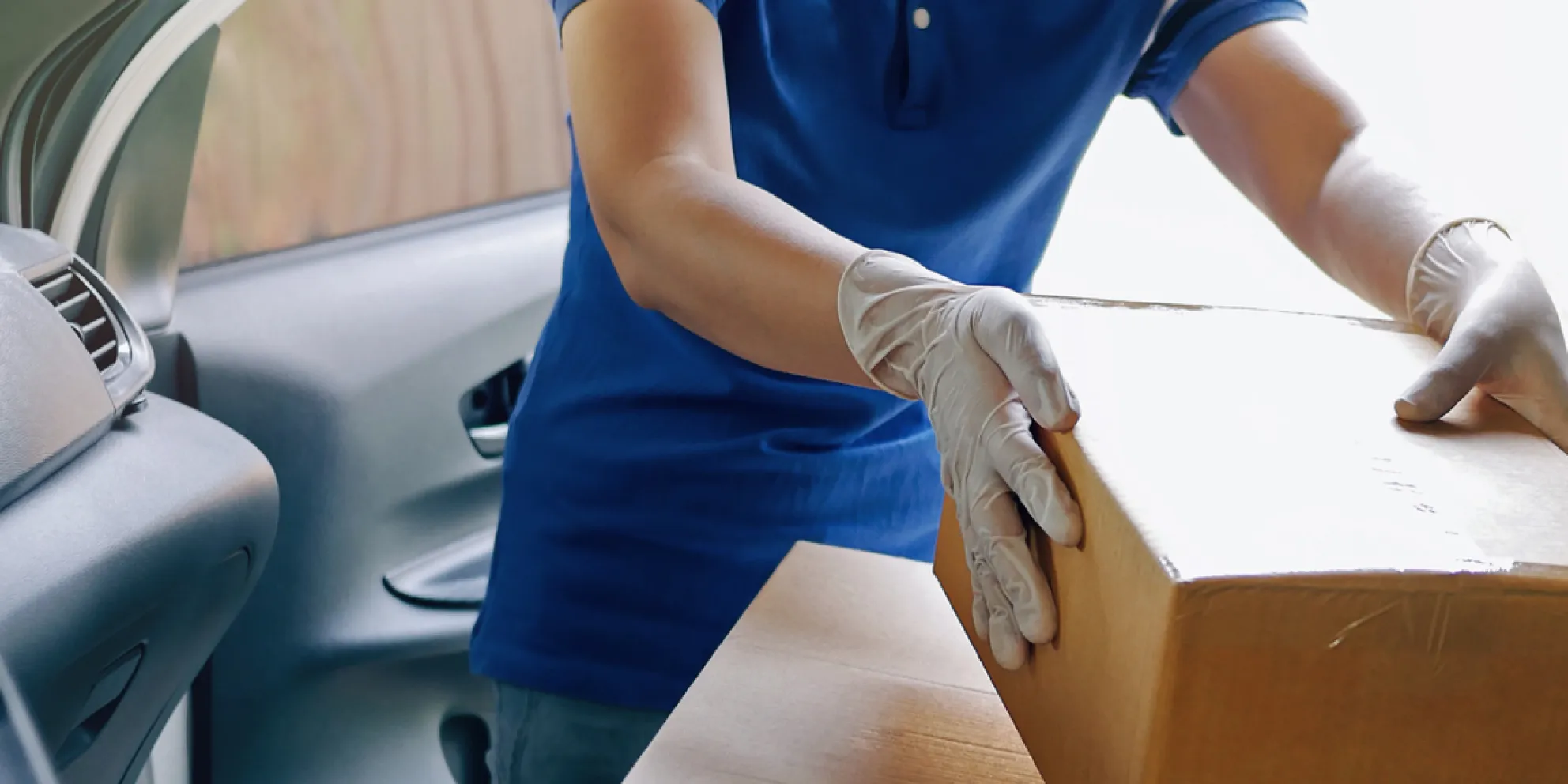 Delivery services courier during the Coronavirus COVID-19 pandemic, courier wearing medical mask and latex gloves for safety protection from virus infection working with cardboard boxes on van seat.jpg