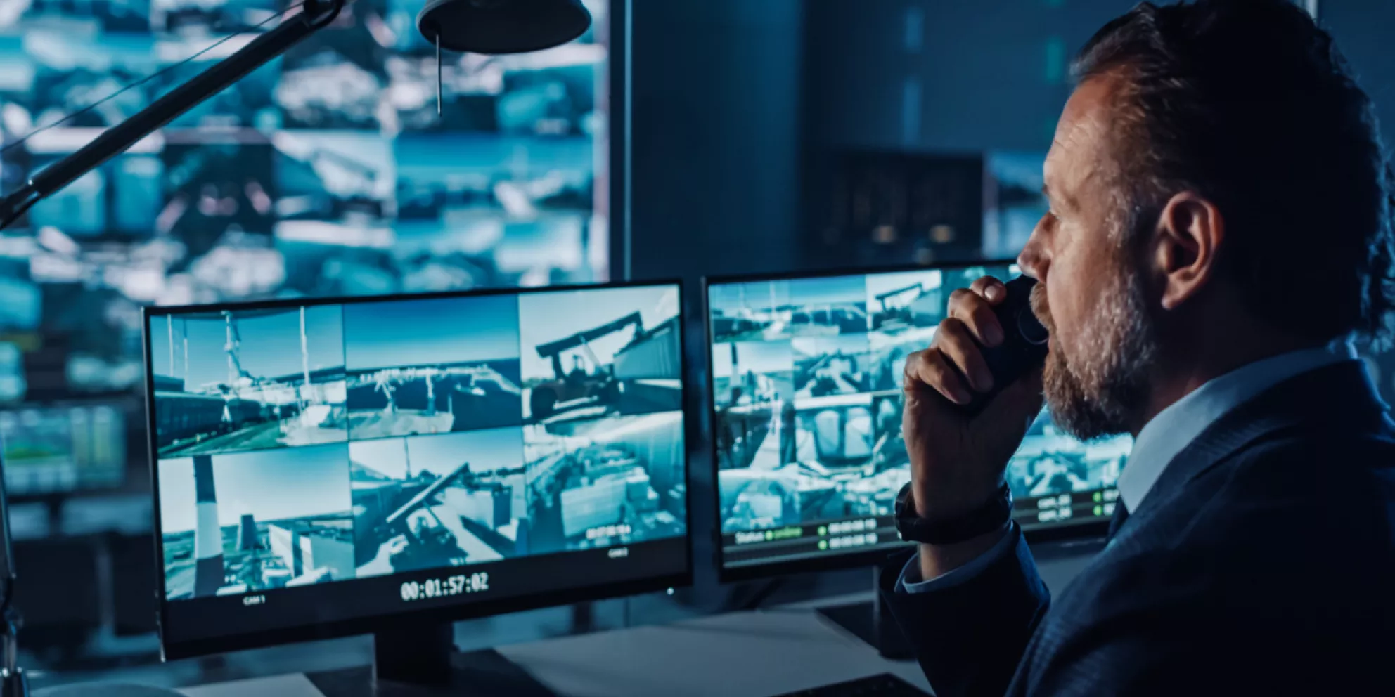 Male Officer Works on a Computer with Surveillance CCTV Video