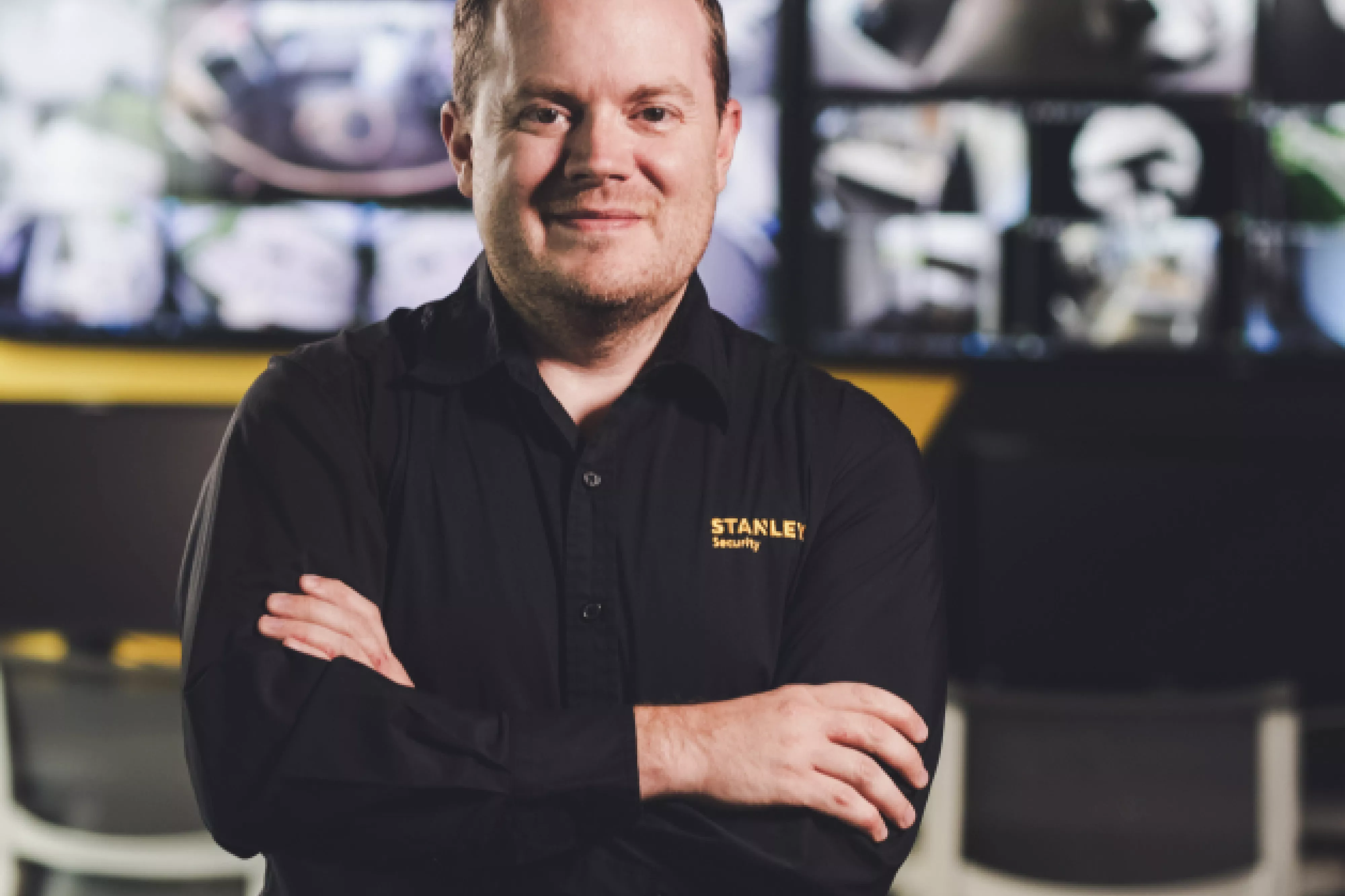 Smiling employee stands with arms crossed