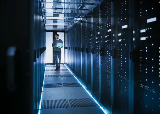 Man met laptop in een datacenter ruimte.