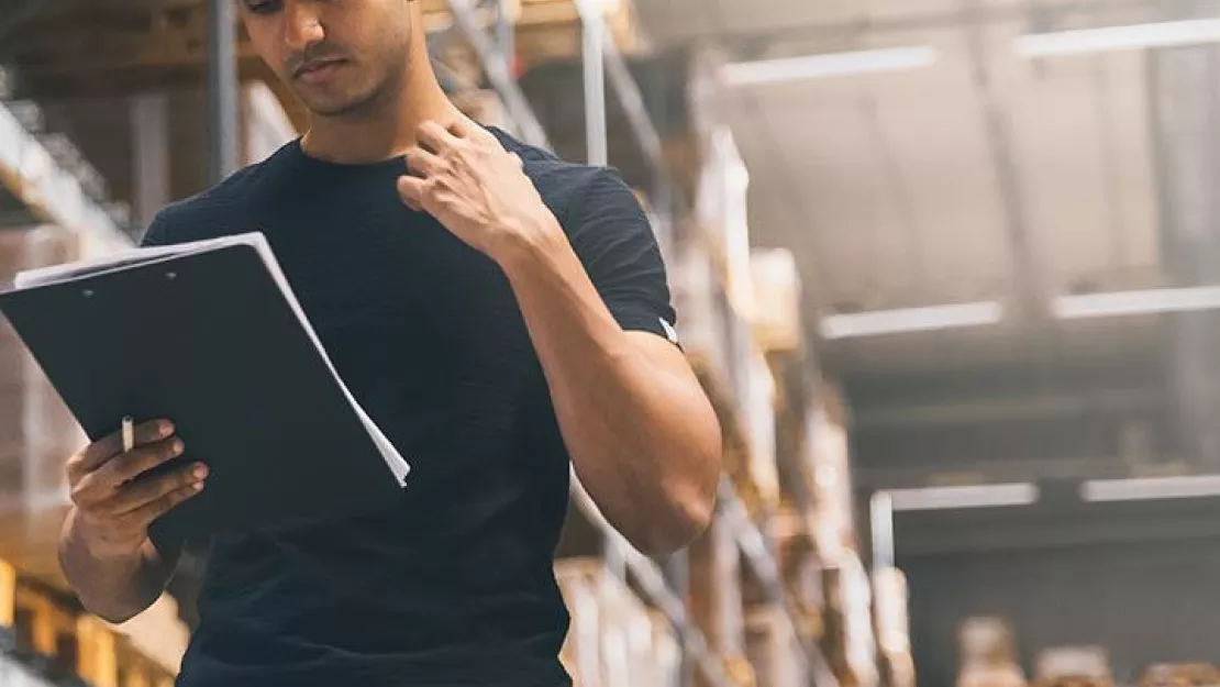 Man in hard hat with clipboard in warehouse