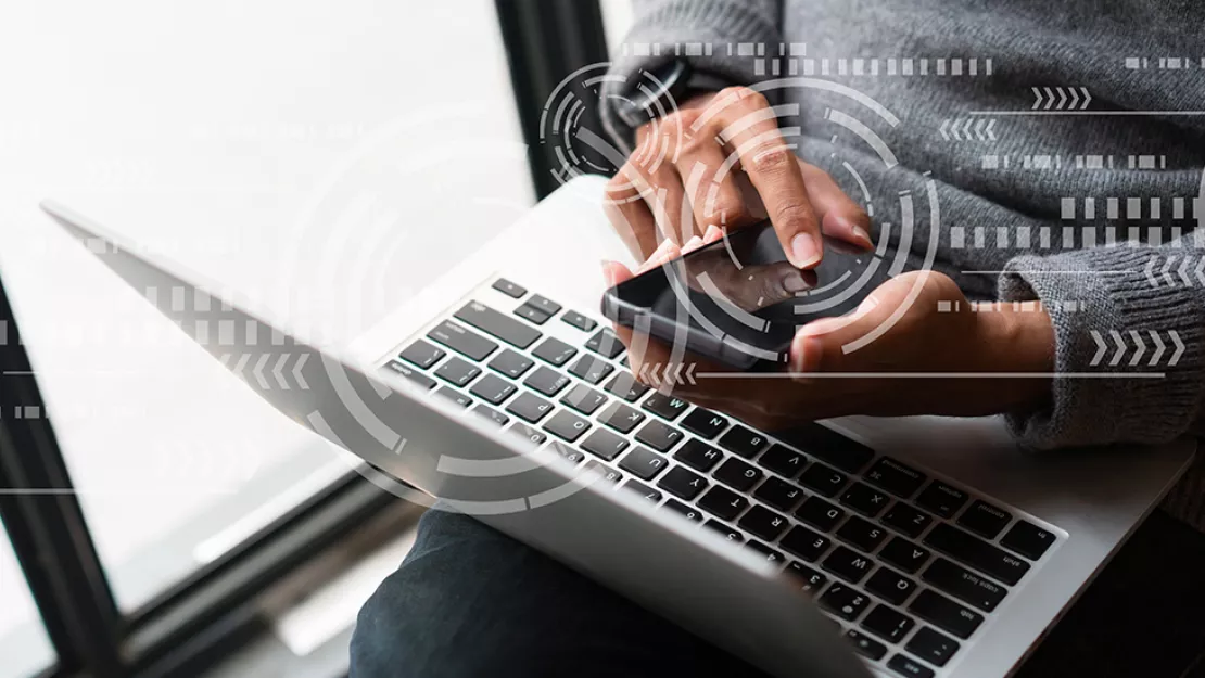 Using laptop and smartphone by window