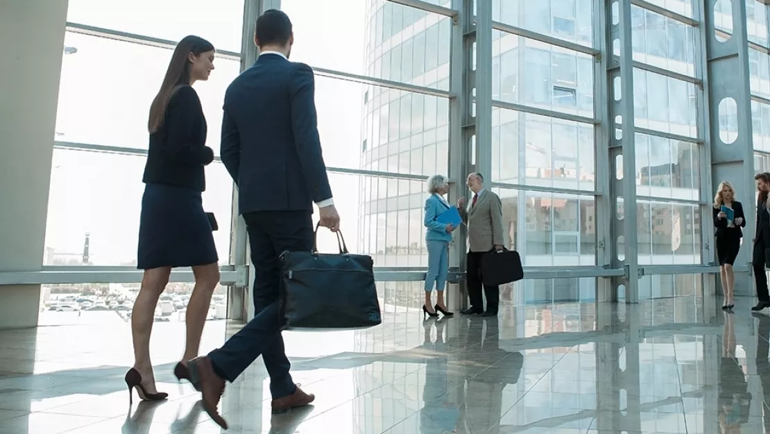 People walk through lobby of glass building