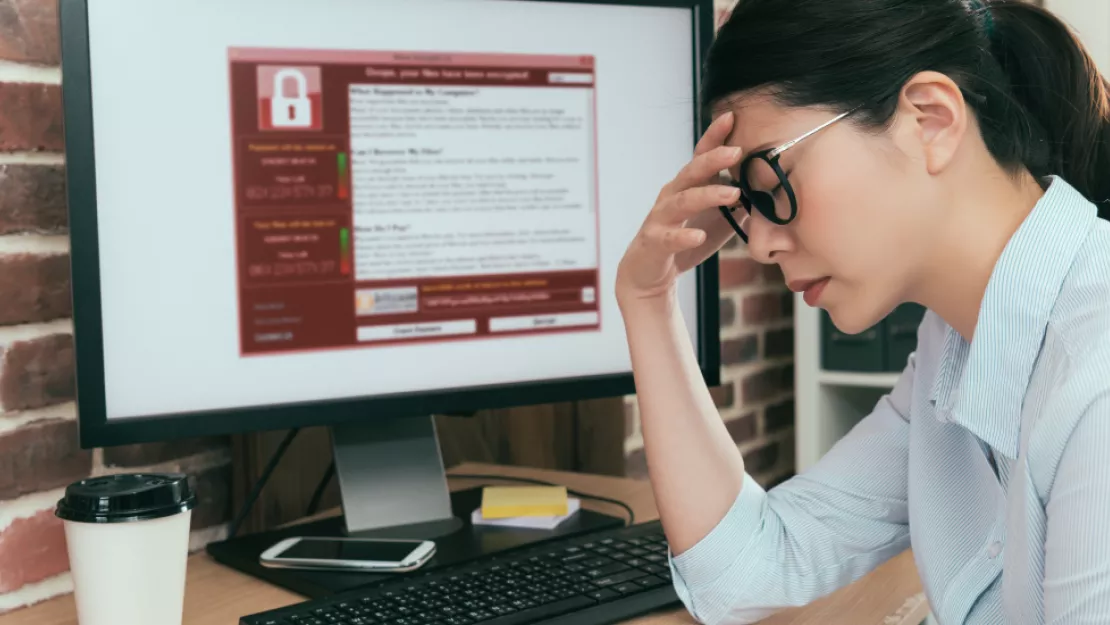 Frustrated woman holds forehead in front of computer