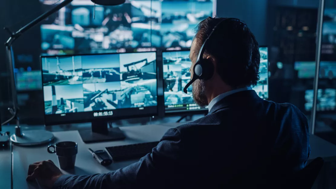 Security operator in alarm centre watching multiple screens.png