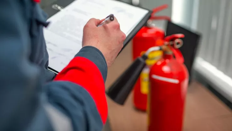 Man with clipboard completes fire safety evaluation.