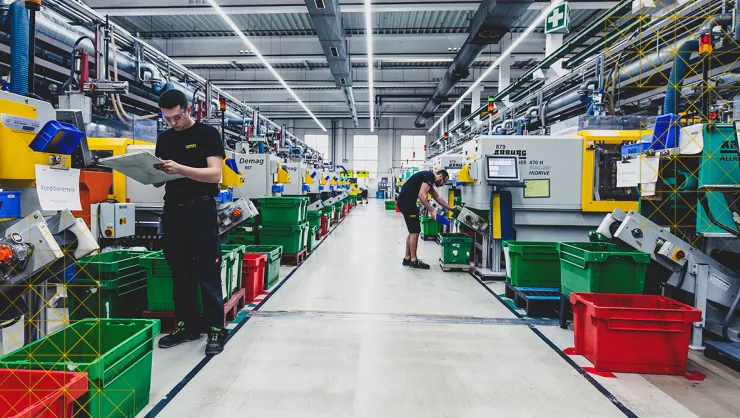 Two men work at manufacturing machines.