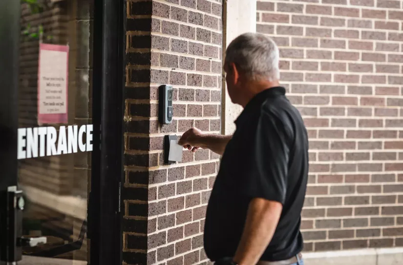 person swiping card reader on door using commercial smart lock access control credentials