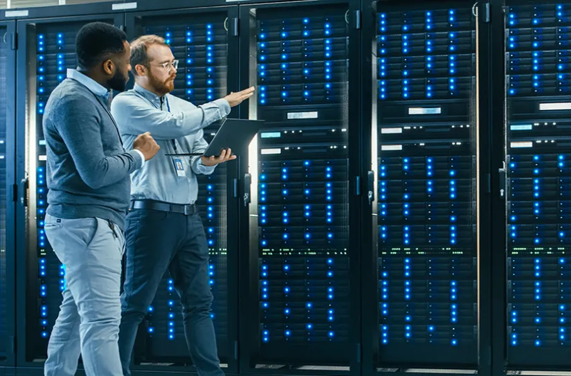 Two IT managers walk past row of servers
