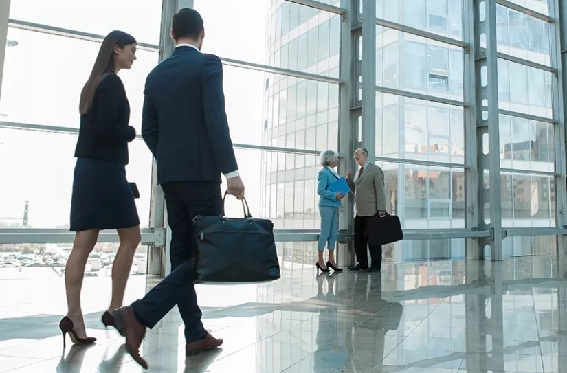 People walk through lobby of glass building