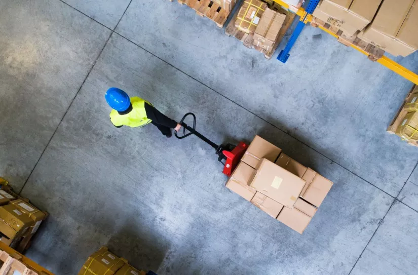 man in warehouse pulling package cart