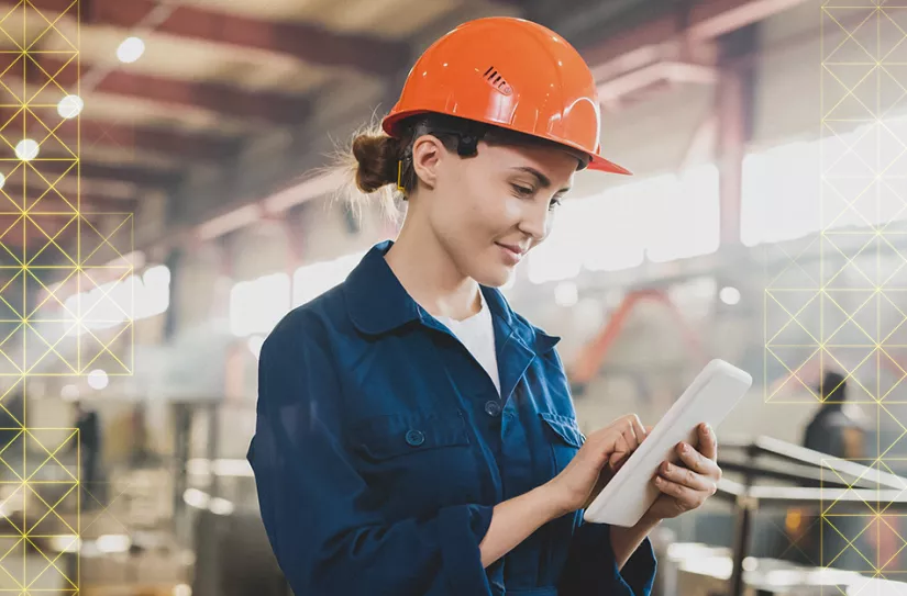 Woman in hardhat uses tablet.