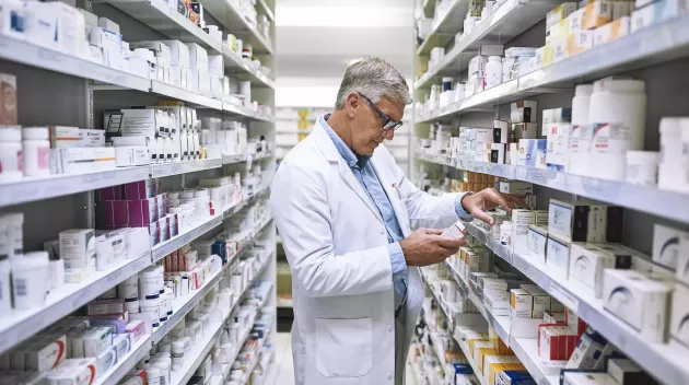 Pharmacy, medicine and search with man at shelf in drug store for thinking, inspection and inventory. Medical, healthcare and pills with senior male pharmacist for expert, wellness and product.