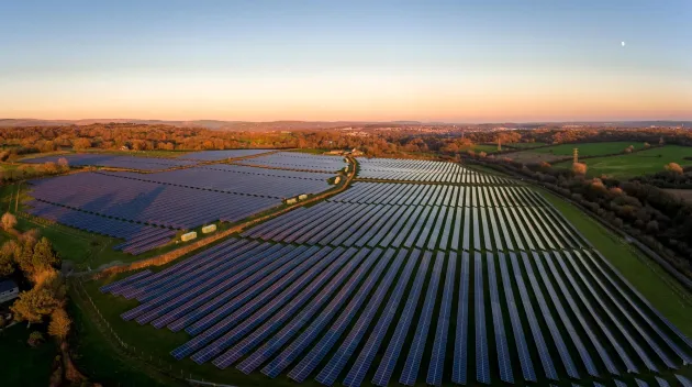 Aerial drone view of solar panels at a solar energy generation farm at Sunset in South Wales, UK