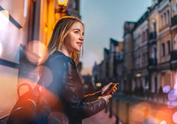 Kvinna använder mobiltelefon för att aktivera personlarm – en del av vår lösning för personlig säkerhet & larm i vardagen