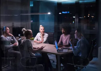 Multiethnic startup business team on meeting in modern night office interior brainstorming, working on laptop