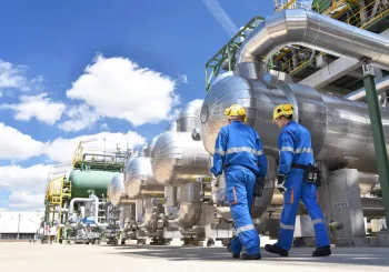 Workers in an industrial plant overseeing the production and processing of crude oil, highlighting safety and critical infrastructure security in the energy sector