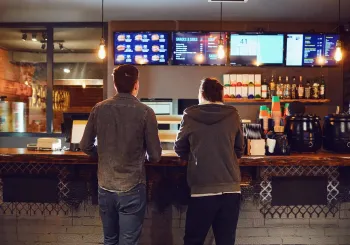 Rear view. Two men choose food in a fast food restaurant. Bar snack concept.