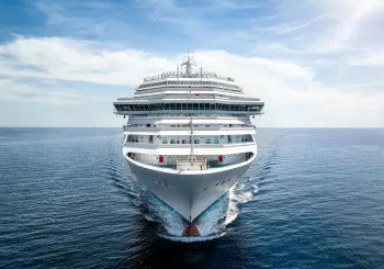Aerial front view of a generic cruise ship traveling with speed over blue ocean