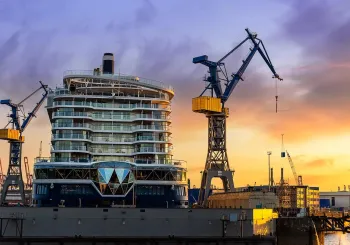 Scenic back view large modern luxury cruise ship liner under construction building cranes at dry dock shipyard in Hamburg port dramatic sunset sky background. Big vessel manufactoring site industry